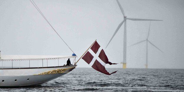 Das Heck eines Schiffes mit dänischer Flagge vor Windanlagen auf See