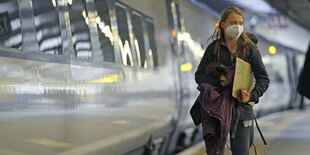 Greta Thunberg auf einen Bahnsteig vor einem Zug.