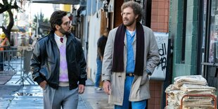 Paul Rudd (l.) und Will Ferrell (r.) laufen auf einer Straße, rechts neben ihnen stapeln sich Zeitungen