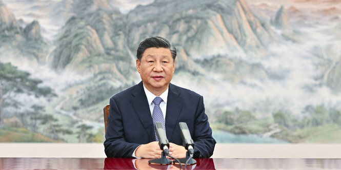 Xi Jinping bei einer Pressekonferenz vor einem Wandgemälde.