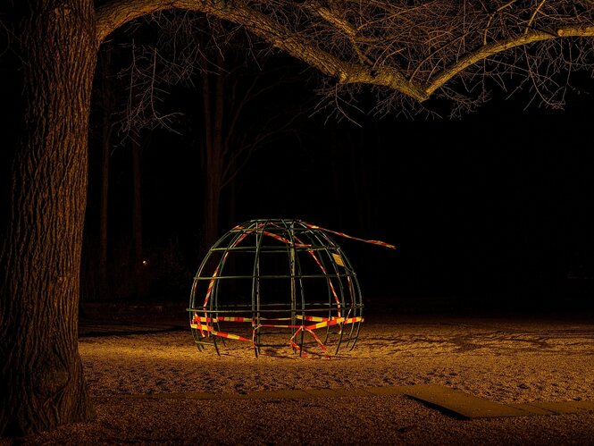 Ein Spielgerät auf einem abgesperrten, nächtlichen Spielplatz