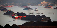 Lastkähne hoch beladen mit Kohlebergen in einem Hafen