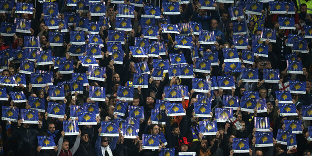 Kosovaren im Stadion halten Kartons hoch, auf denen die Landesgrenzen abgebildet sind