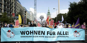 Viele Aktivisti*innen laufen auf der Straße hinter einem Transparent mit der Aufschrift "Wohnen für alle"