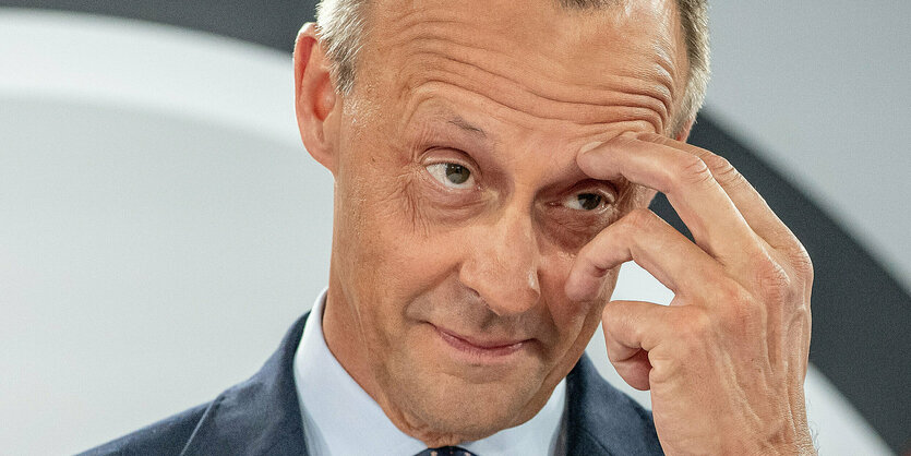 Friedrich Merz greif sich mit seiner linken Hand an sein linkes Auge