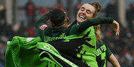 Die Wolfs­burgerinnen Jill Roord (r.) und Shanice van de Sanden schlingen Arme und eine Decke umeinander.