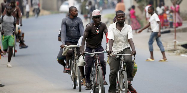 Drei Männer auf Fahrrädern auf der Straße
