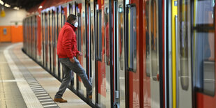 Mann mit Maske steigt in eine Bahn.