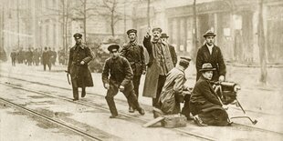 Eine alte Fotografie mit kämpfenden Berlinern, den sogenannte Spartakisten auf einer Straße mit einem alten Maschinengewehr