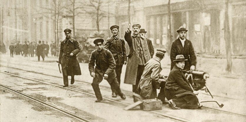 Eine alte Fotografie mit kämpfenden Berlinern, den sogenannte Spartakisten auf einer Straße mit einem alten Maschinengewehr