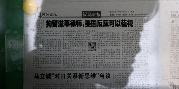 Silhouette von einem Kopf vor einer chinesischen Zeitung.