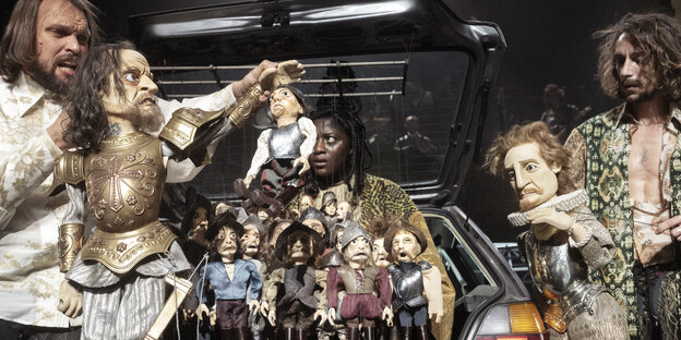 Schauspieler und Puppen, die wie Konquistadoren gekleidet sind, gruppieren sich um die Heckklappe eines Autos