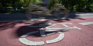 Verwischter Radfahrer auf rot bemaltem Fahrradstreifen