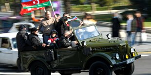 Menschen auf einem Jeep mit Flagge.