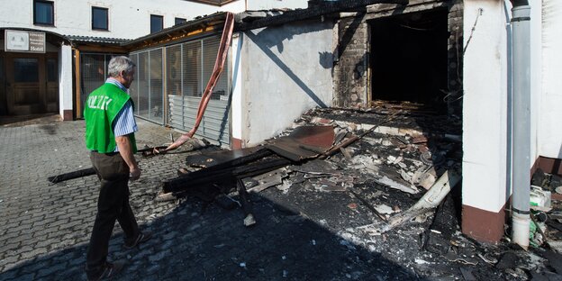 Feuerwehrmann löscht brennendes Dach einer geplanten Flüchtlingsunterkunft.