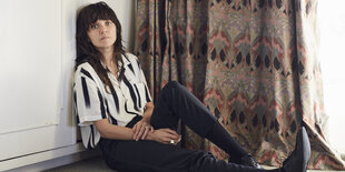 Courtney Barnett sitzt am Fenster neben dem Vorhang