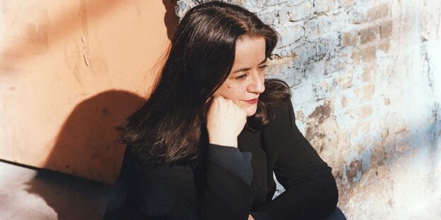 Eleni Karaindrou sitzt vor einer Wand