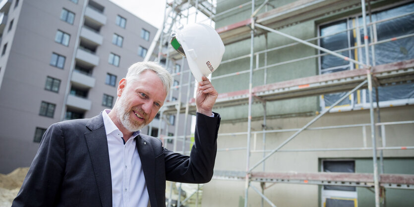 Sebastain Scheel mit gezücktem Bauhelm auf einer Baustelle