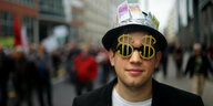 Ein ePerson mit Geldscheinen am Hut und einer Dollarzeichenbrille.