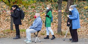 Vier Menschen sitzen oder stehen in einer Schlange