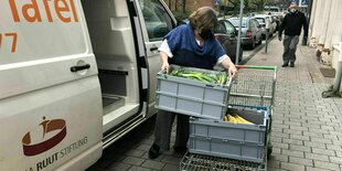 Eine Frau lädt Kisten aus einem Transporter, auf dem "Tafel" steht