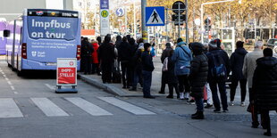 Menschen in einer Schlange vor einem Impfbus.