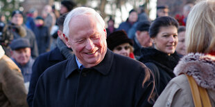 Ein älterer Herr . Oskar Lafontaine mit wenigen weißen Haaren in einer Menschenmenge. Im Hintergrund seine Frau Sahra Wagenknecht.