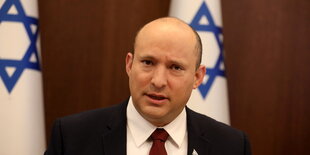 Premierminister Naftali Bennett vor israelischen Flaggen.