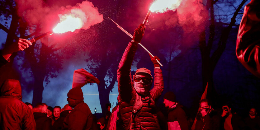 Menschen verbrennen Bengalos, während sie an einer Demonstration gegen die Coronavirus-Beschränkungen des Landes teilnehmen