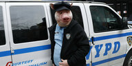 Ein als Polizist mit Schweinemaske verkleidete Person vor einem New Yorker Polizeiauto