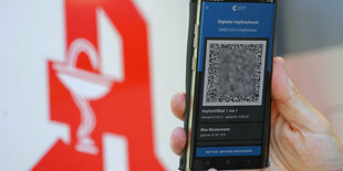 Der digitale Impfnachweis ist vor dem Apotheken-Logo auf einem Smartphone zu sehen. Eine Mitarbeiterin einer Münchner Apotheke soll gemeinsam mit Komplizen dafür nötige QR-Codes gefälscht und im Internet verkauft haben