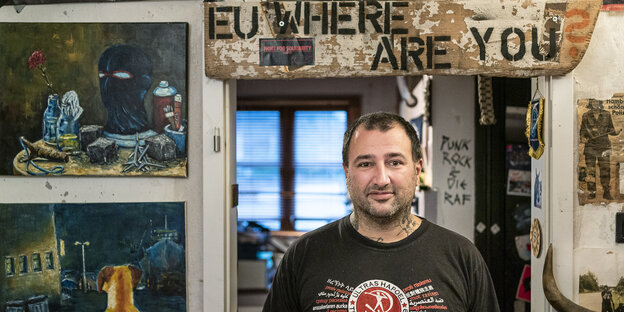 Dariush Beigui steht in einem Türrahmen, daneben Punk-Poster