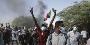 Menschen bei einer Demo: Im Fokus ist ein junger Mann, der mit beiden Händen das Victory-Zeichen zeigt