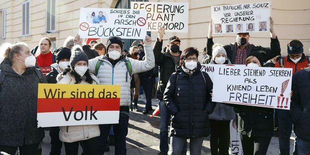 Impfgegner auf einer Demo in Wien halten Schilder hoch