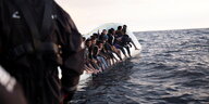Migranten sitzen auf einem Gummiboot auf dem Meer während einer Rettungsaktion