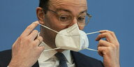 Jens Spahn setzt eine Mund-Nasen-Maske auf