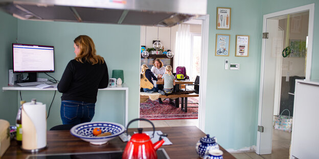 Frau steht in einer Küche mit Computerecke