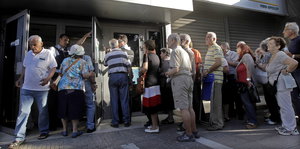 Rentner stehen vor einem Bankeingang