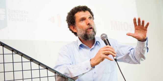 Osman Kavala steht an einem Mikrofon