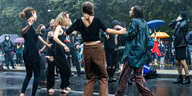 Junge Menschen tanzen im Regen während einer Mietendemo