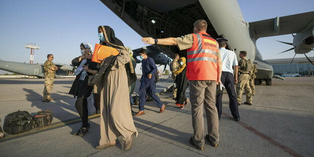 Schutzbedürftige Menschen betreten kurz nach dem Flug aus Kabul sicheren Boden zum Weiterflug nach Deutschland.