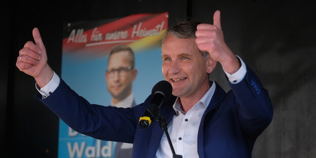 Der Rechtsextreme Björn Höcke hebt bei einer Wahlkampfveranstaltung beide Daumen und lächelt.