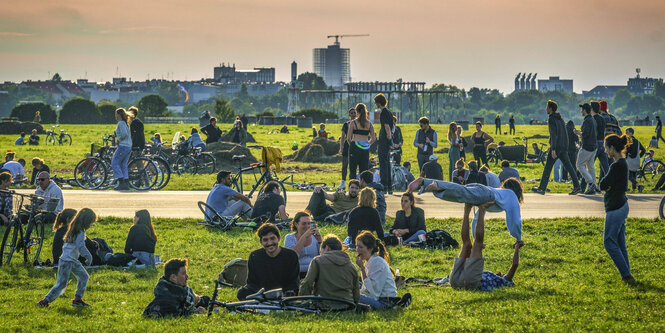 Menschen sitzen auf einer Grünfläche zusammen