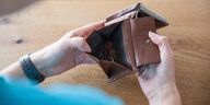 Eine Frau hält ein Portemonnaie in den Händen, in der Geldbörse sind verschiedene Eurostücke.