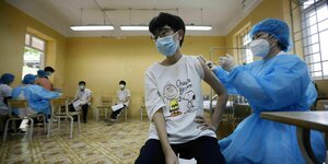 Eine Junge erhält von einer Krankenschwester eine Corona-Impfung