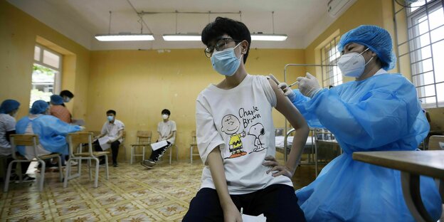 Eine Junge erhält von einer Krankenschwester eine Corona-Impfung
