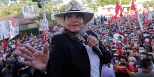 Frau mit Hut und Mikrophon vor einer Menschenmenge