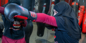 Eine junge boxende Frau mit Boxhandschuhen und Kopftuch