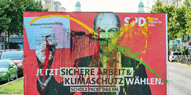 Auf einem wahlplakat der SPD st das Bild von Kanzlerkandidat Scholz mit Farbe bespritzt