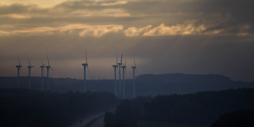 Windräder und eine Autobahn unter düsterem Wolkenhimmel